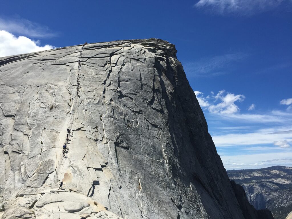 view of people walking up the Half Dome cables on a sunny day in Yosemite, National Park