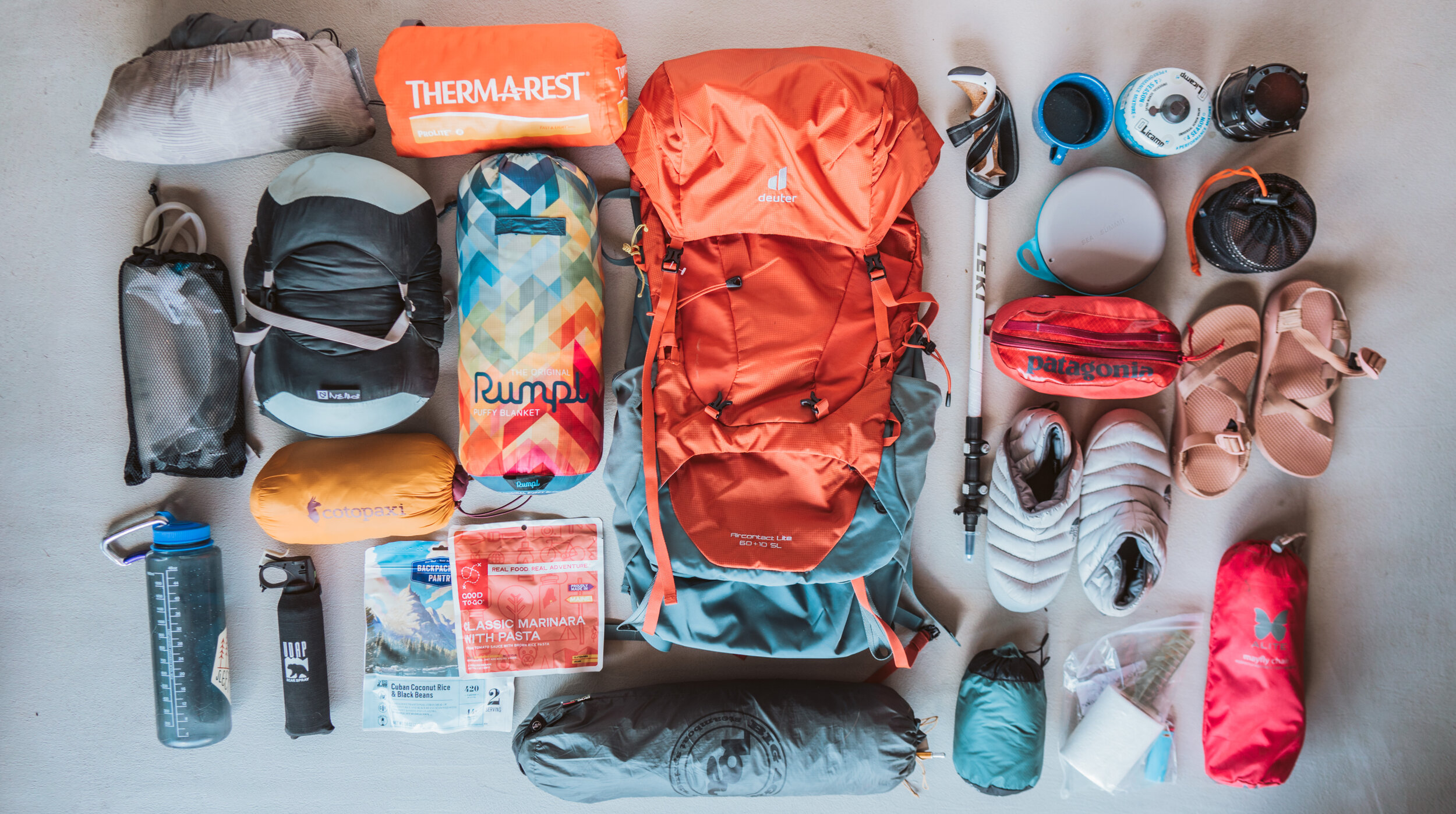 a layflat display of everything packed into a woman's backpack for an overnight adventure