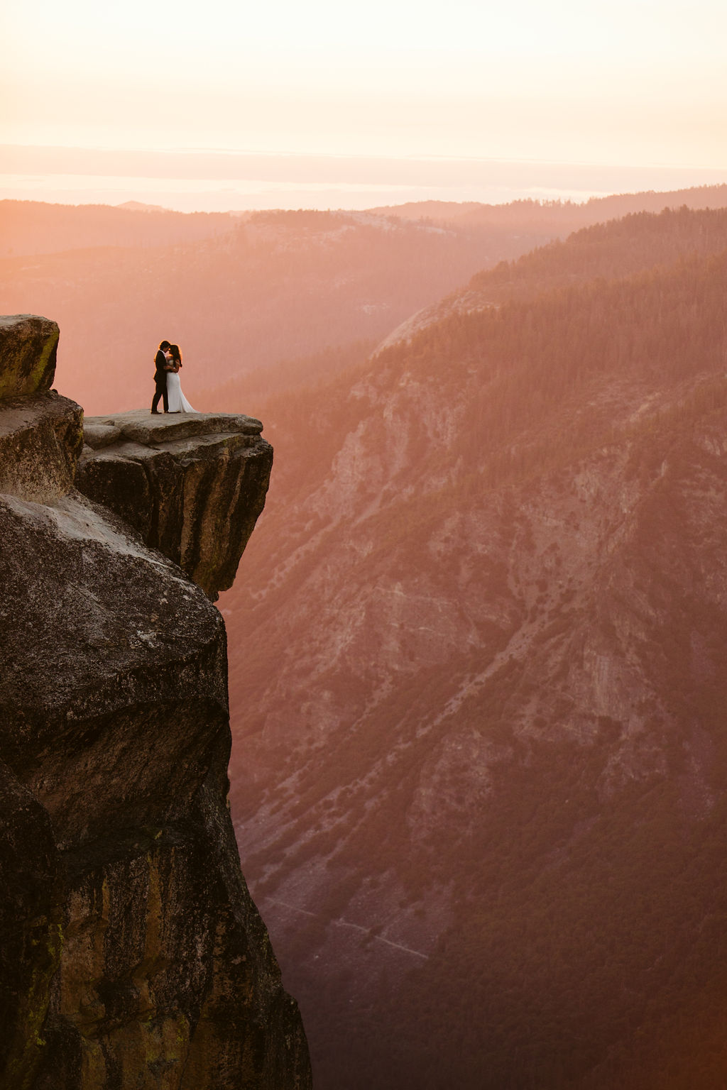A bride and groom standing on ledge of lookout at Yosemite National Park in an adventure elopement photoshoot