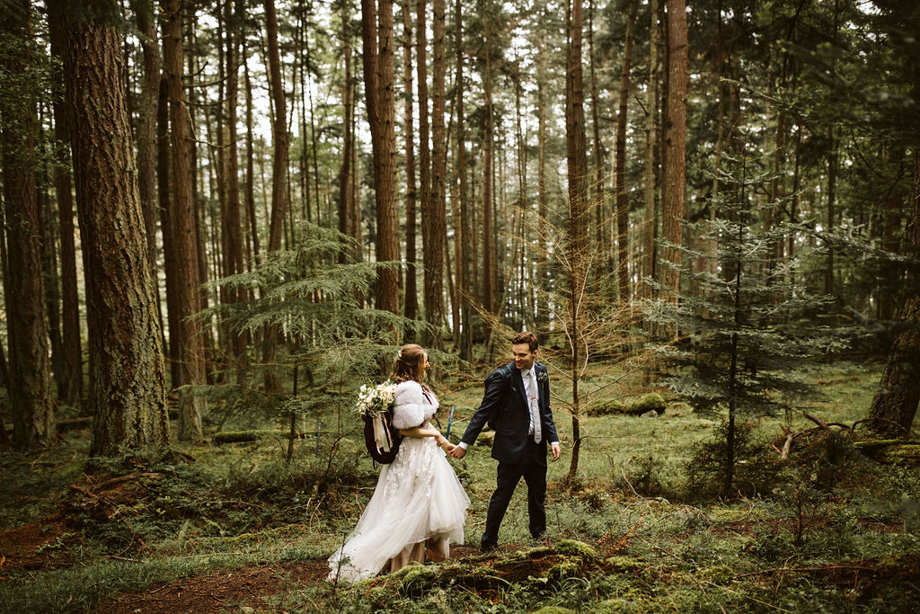 A bride and groom walk through the woods for their pacific north west elopement photoshoot with photographer Kelly Lemon